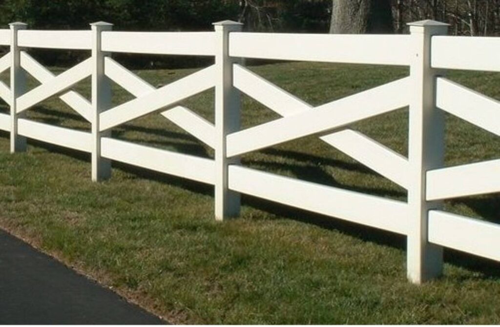 Several rows of white wooden fences with diagonal cross members, set against a grassy lawn.